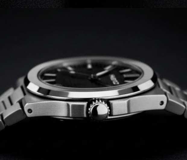 Close-up of a silver watch with a dark face on a black background